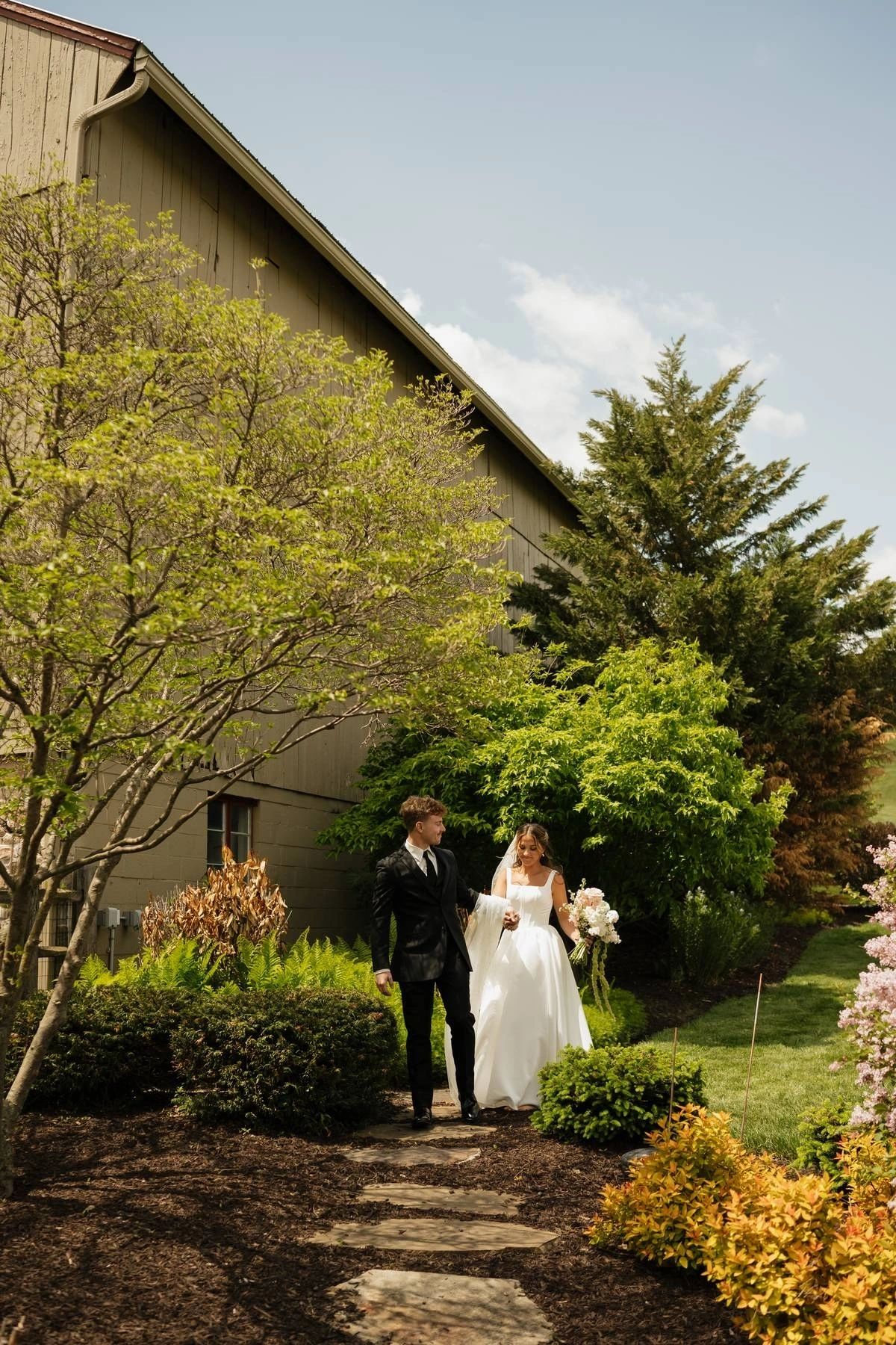Newlyweds embracing in the garden beside the venue building