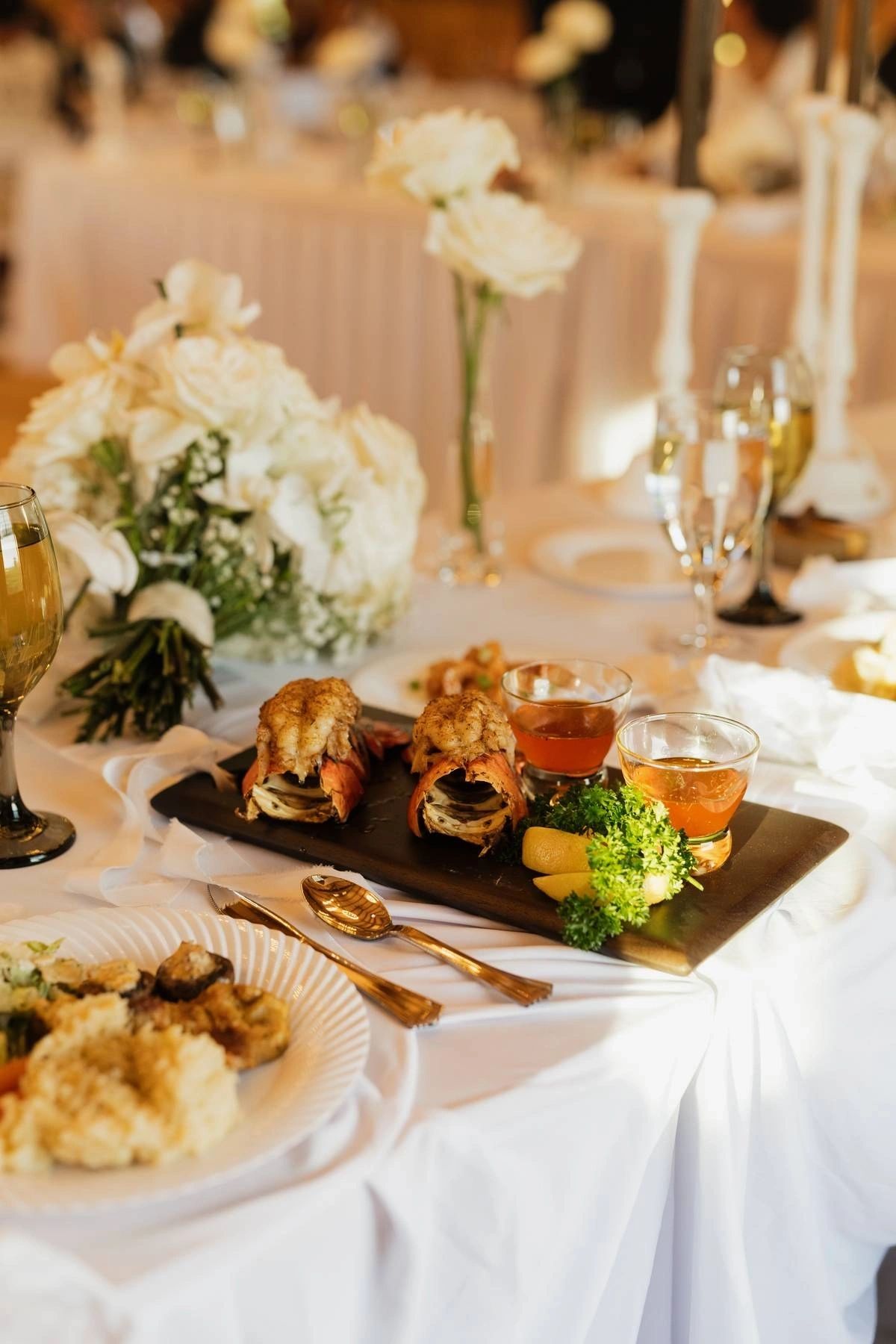Plated buffet service on a linen table beside white floral centerpieces at a Lancaster County reception