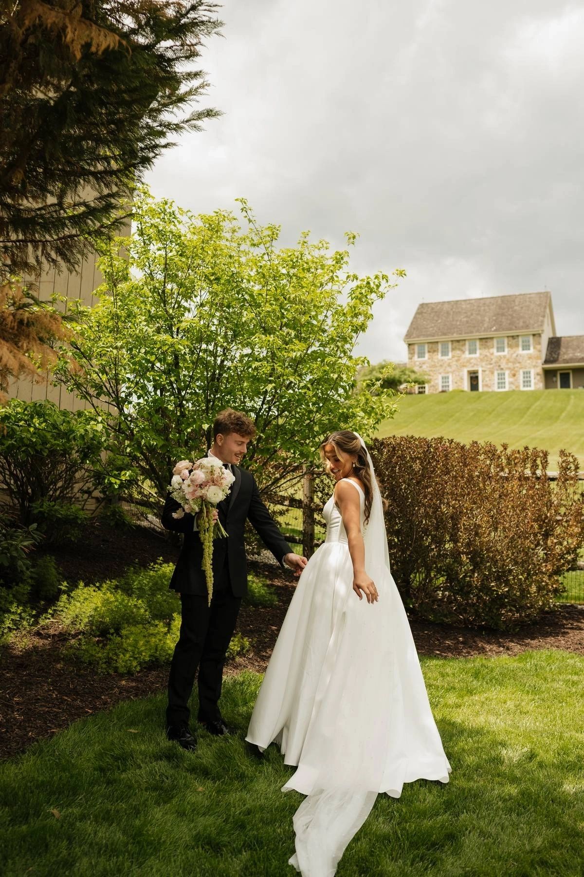 Bride and groom with bouquet beneath a tree on the venue grounds