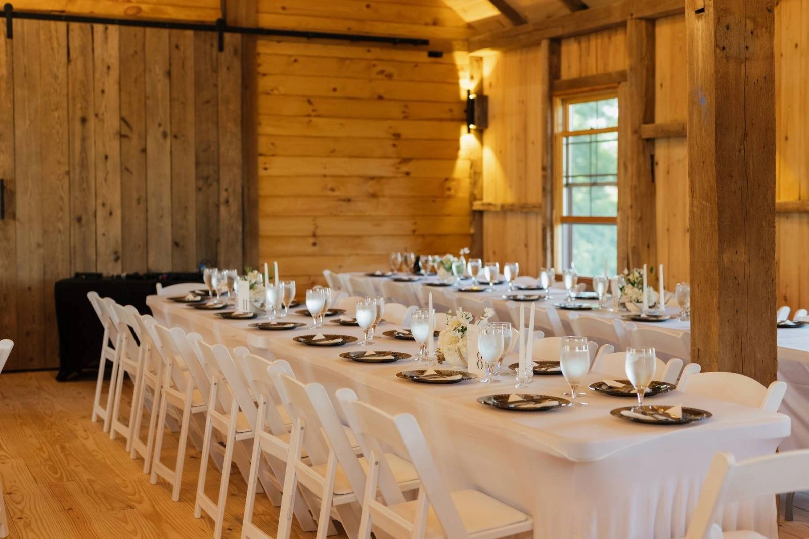 Long banquet table set with white linens and place settings in the wood-paneled hall