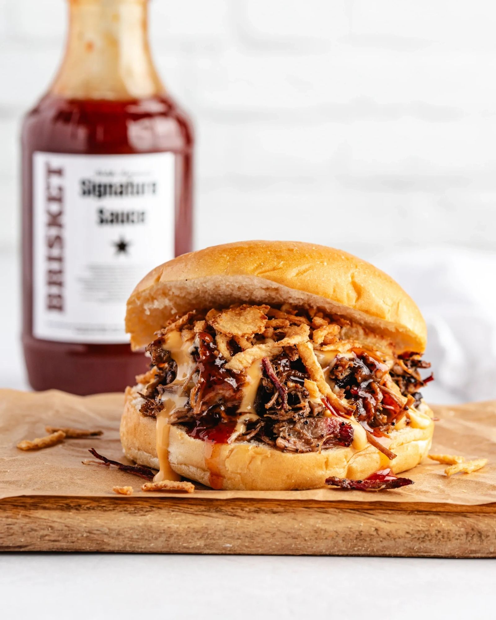 Pulled beef brisket sandwich with crispy onions and signature sauce